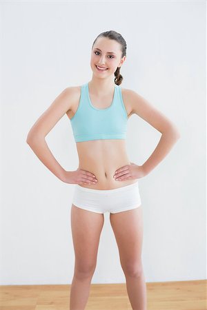 simsearch:400-07136501,k - Portrait of a smiling toned young woman with hands on hips in fitness studio Photographie de stock - Aubaine LD & Abonnement, Code: 400-07136490