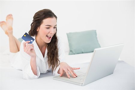 Casual young woman doing online shopping through laptop and credit card in bed Stock Photo - Budget Royalty-Free & Subscription, Code: 400-07136612