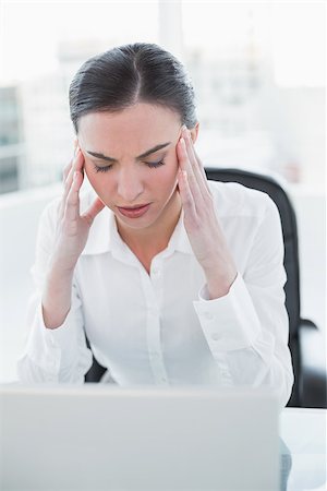 Young businesswoman suffering from headache in front of laptop at office desk Stock Photo - Budget Royalty-Free & Subscription, Code: 400-07136936