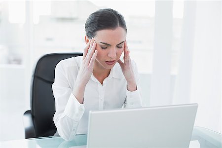 Young businesswoman suffering from headache in front of laptop at office desk Stock Photo - Budget Royalty-Free & Subscription, Code: 400-07136937