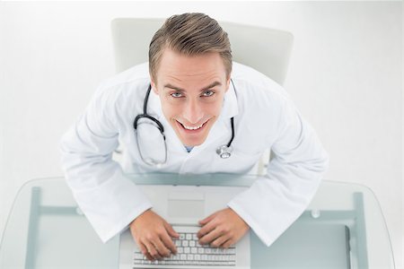 simsearch:695-05771285,k - Overhead portrait of a smiling male doctor using laptop at medical office Foto de stock - Royalty-Free Super Valor e Assinatura, Número: 400-07136987