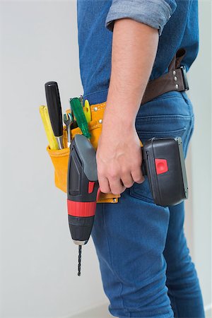 Side view mid section of a handyman with drill and toolbelt by the wall Stock Photo - Budget Royalty-Free & Subscription, Code: 400-07137042