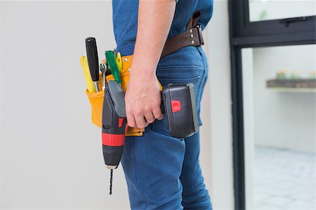 Side view mid section of a handyman with drill and toolbelt by the wall Stock Photo - Budget Royalty-Free & Subscription, Code: 400-07137043