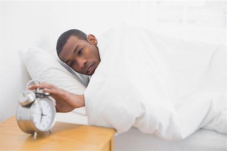 simsearch:614-02613098,k - Young Afro man in bed extending hand to alarm clock Stockbilder - Microstock & Abonnement, Bildnummer: 400-07137465