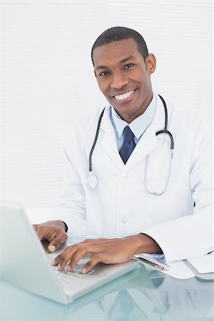 simsearch:695-05771285,k - Portrait of a smiling male doctor using laptop at medical office Foto de stock - Royalty-Free Super Valor e Assinatura, Número: 400-07137500