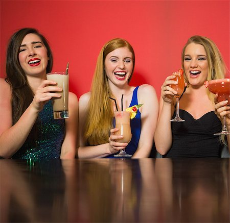 simsearch:649-06844392,k - Laughing friends holding cocktails and looking at camera in a nightclub Stock Photo - Budget Royalty-Free & Subscription, Code: 400-07137882