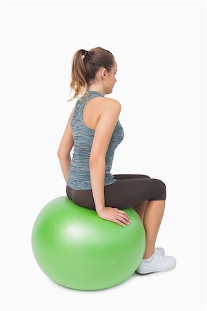 Side view of ponytailed woman sitting on fitness ball on white background Stock Photo - Budget Royalty-Free & Subscription, Code: 400-07138166