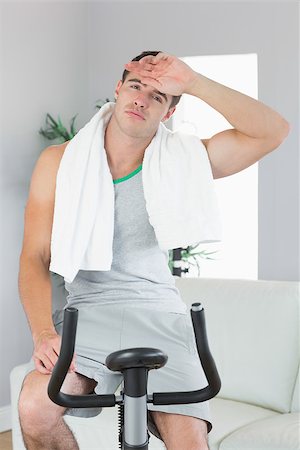 Tired handsome man exercising on exercise bike in bright living room Stock Photo - Budget Royalty-Free & Subscription, Code: 400-07138391