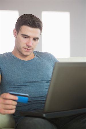 simsearch:400-07474252,k - Content handsome man relaxing on couch using laptop shopping online in bright living room Stock Photo - Budget Royalty-Free & Subscription, Code: 400-07138458