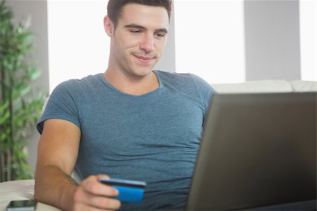 simsearch:400-07474252,k - Happy handsome man relaxing on couch using laptop shopping online in bright living room Stock Photo - Budget Royalty-Free & Subscription, Code: 400-07138461