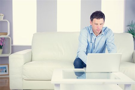 Attractive casual man using laptop in bright living room Stock Photo - Budget Royalty-Free & Subscription, Code: 400-07139024