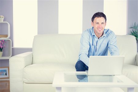 Smiling casual man using laptop in bright living room Stock Photo - Budget Royalty-Free & Subscription, Code: 400-07139025