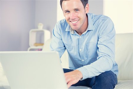 Cheerful casual man using laptop and looking at camera in bright living room Stock Photo - Budget Royalty-Free & Subscription, Code: 400-07139023
