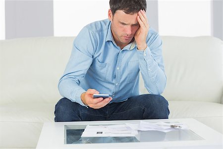 simsearch:400-07333928,k - Upset casual man using calculator paying bills in bright living room Stock Photo - Budget Royalty-Free & Subscription, Code: 400-07139089