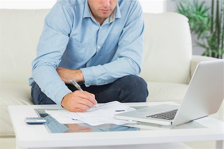 simsearch:400-07333928,k - Close up of man writing on sheets paying bills in bright living room Stock Photo - Budget Royalty-Free & Subscription, Code: 400-07139096