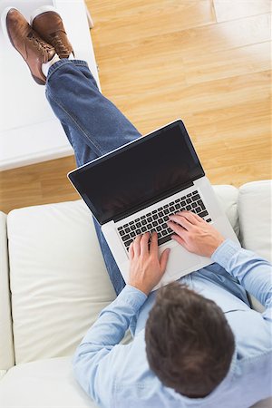 High angle view of casual man typing on laptop with feet on table in bright living room Stock Photo - Budget Royalty-Free & Subscription, Code: 400-07139103