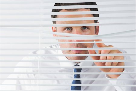 Handsome businessman spying through roller blind Stock Photo - Budget Royalty-Free & Subscription, Code: 400-07139157