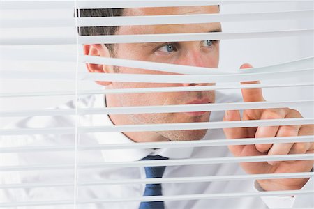 Attractive businessman spying through roller blind Stock Photo - Budget Royalty-Free & Subscription, Code: 400-07139158