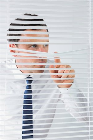 Good looking businessman spying through roller blind Stock Photo - Budget Royalty-Free & Subscription, Code: 400-07139159
