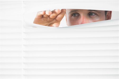 peeking store window - Close up of male blue eyes spying through roller blind Photographie de stock - Aubaine LD & Abonnement, Code: 400-07139164