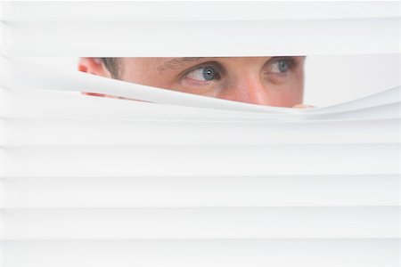 Male blue eyes spying through roller blind Fotografie stock - Microstock e Abbonamento, Codice: 400-07139161