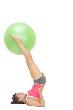 simsearch:400-07139290,k - Content sporty brunette holding exercise ball between legs on white background Stock Photo - Budget Royalty-Free & Subscription, Code: 400-07139209