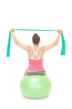 simsearch:400-07139290,k - Sporty brunette stretching with resistance band sitting on exercise ball on white background Stock Photo - Budget Royalty-Free & Subscription, Code: 400-07139218