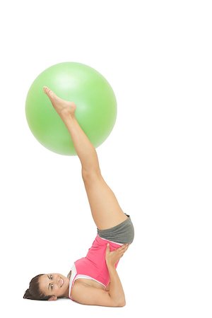 simsearch:400-07139290,k - Smiling sporty brunette holding exercise ball between legs on white background Stock Photo - Budget Royalty-Free & Subscription, Code: 400-07139210