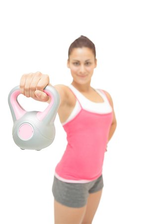 simsearch:400-07139290,k - Smiling sporty brunette showing grey and pink kettlebell on white background Stock Photo - Budget Royalty-Free & Subscription, Code: 400-07139271