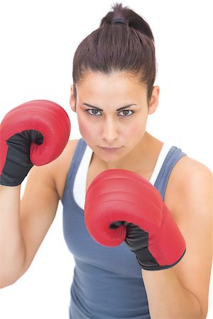 simsearch:400-07139290,k - Stern sporty brunette wearing red boxing gloves on white background Stock Photo - Budget Royalty-Free & Subscription, Code: 400-07139281
