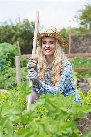 simsearch:400-07927044,k - Smiling young woman holding a rake looking at the camera in her garden Stock Photo - Budget Royalty-Free & Subscription, Code: 400-07139546
