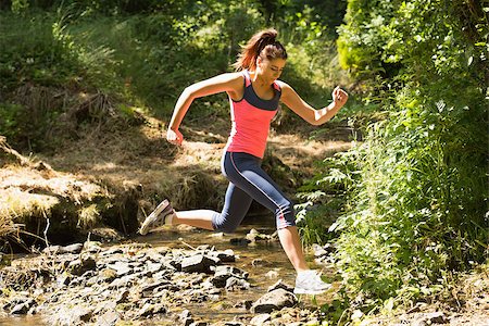 Sporty young woman leaping over a stream in a forest on a run Stock Photo - Budget Royalty-Free & Subscription, Code: 400-07139826