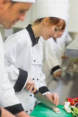 simsearch:400-07140008,k - Pretty chef slicing mushrooms with colleagues in commercial kitchen Photographie de stock - Aubaine LD & Abonnement, Code: 400-07139959
