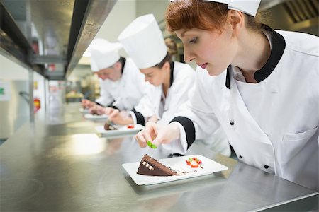 restaurant work teenager - Chefs standing in a row garnishing dessert plates in the kitchen Photographie de stock - Aubaine LD & Abonnement, Code: 400-07139975