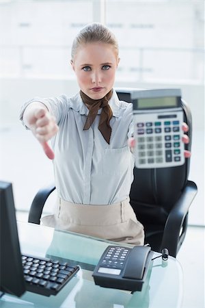 Blonde stern businesswoman showing calculator and thumb down in bright office Stock Photo - Budget Royalty-Free & Subscription, Code: 400-07130726