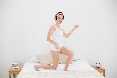 Pretty woman playing air guitar on her bed while listening to music Stock Photo - Budget Royalty-Free & Subscription, Code: 400-07131104