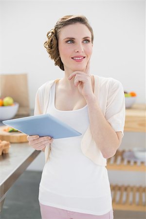 Smiling thinking woman holding her tablet standing in kitchen at home Stock Photo - Budget Royalty-Free & Subscription, Code: 400-07131238