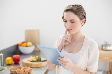 Concentrating young woman using her tablet standing in her kitchen at home Stock Photo - Budget Royalty-Free & Subscription, Code: 400-07131242
