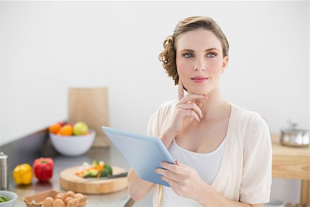 Young thoughtful woman standing in kitchen holing her tablet at home Stock Photo - Budget Royalty-Free & Subscription, Code: 400-07131243