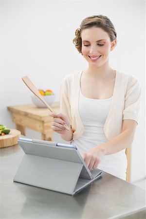Smiling brunette woman standing in her kitchen while working with her tablet at home Stock Photo - Budget Royalty-Free & Subscription, Code: 400-07131306