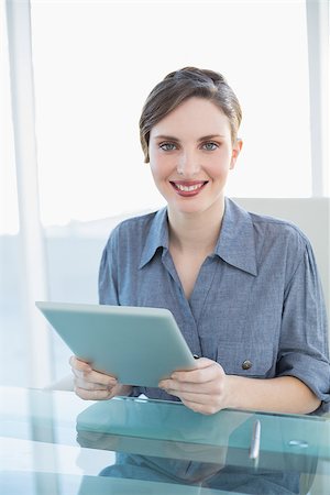 Beautiful businesswoman holding her tablet sitting at her desk smiling at camera Stock Photo - Budget Royalty-Free & Subscription, Code: 400-07131422