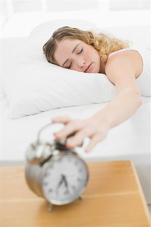 Pretty content blonde lying in bed turning off alarm clock in bright bedroom Photographie de stock - Aubaine LD & Abonnement, Code: 400-07132425