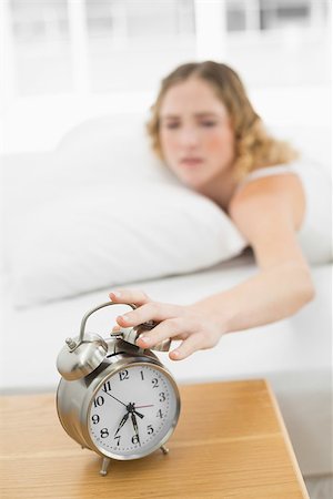 Pretty annoyed blonde lying in bed turning off alarm clock in bright bedroom Photographie de stock - Aubaine LD & Abonnement, Code: 400-07132427