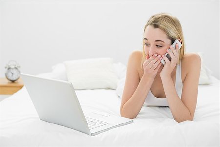 shocked teen computer - Beautiful shocked woman phoning while lying on her bed looking at laptop at home Stock Photo - Budget Royalty-Free & Subscription, Code: 400-07132718