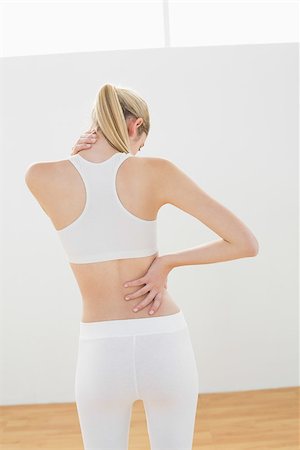 simsearch:400-07138263,k - Sporty blonde woman touching her injured nape standing in sports hall Stock Photo - Budget Royalty-Free & Subscription, Code: 400-07132801