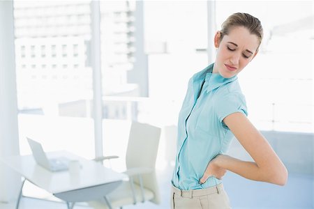 Gorgeous suffering businesswoman holding her injured back standing in her office Stock Photo - Budget Royalty-Free & Subscription, Code: 400-07132905