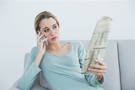 simsearch:400-07716434,k - Casual thinking woman phoning while sitting on couch and holding newspaper Stockbilder - Microstock & Abonnement, Bildnummer: 400-07133075
