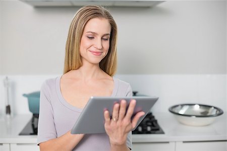 Smiling gorgeous model using tablet standing in kitchen Stock Photo - Budget Royalty-Free & Subscription, Code: 400-07133119