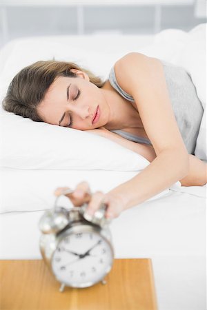 simsearch:614-02613098,k - Attractive woman turning off the alarm clock lying on her bed with eyes closed Stockbilder - Microstock & Abonnement, Bildnummer: 400-07133551