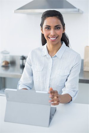 Content woman using her tablet smiling at camera standing in bright kitchen Stock Photo - Budget Royalty-Free & Subscription, Code: 400-07133934